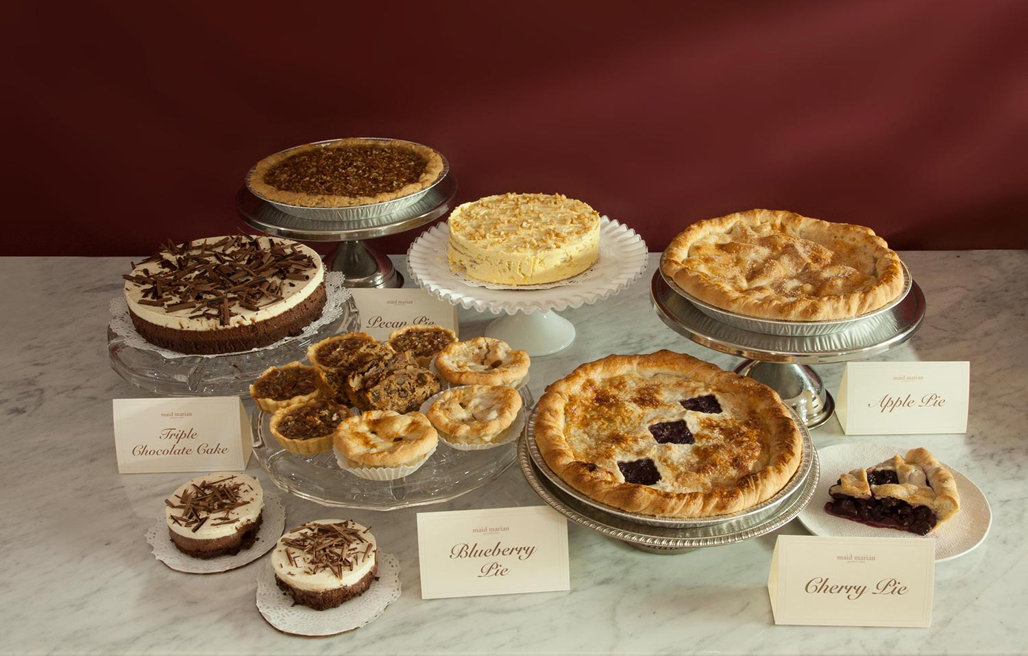 various cakes and pies likes sansrival, apple, cherry, blueberry pies and slices with a red background